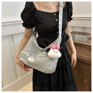 Gros plan d'un grand sac cabas gris clair aspect métallisé avec charm en peluche doux