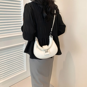 Sac demi-lune blanc avec papillon argenté porté par un mannequin en extérieur