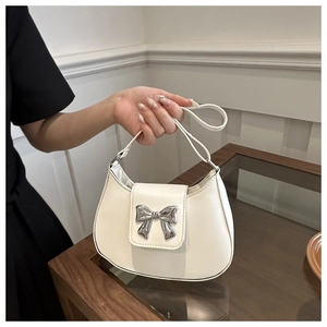 Detail of hobo handbag with silver metal bow and cream leather finish in hand