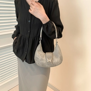 Sac sous le bras croissant argenté avec boucle papillon porté par un mannequin en décor épuré