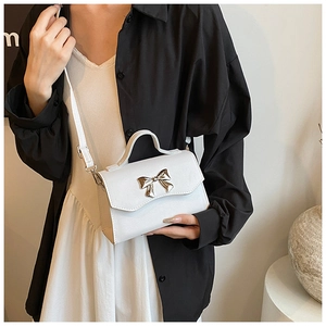 Detail of white leather crossbody bag with golden butterfly clasp and top handle
