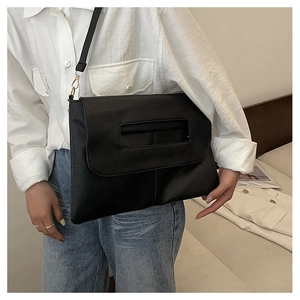 Détail du sac bandoulière enveloppe noir avec texture litchi et boucle en métal doré