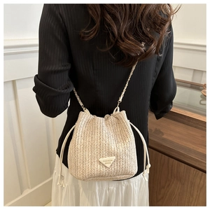Detailed view of straw bucket bag with leather drawstring and gold chain strap