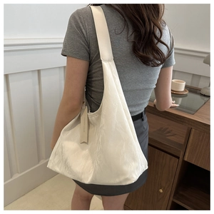 Détail du grand sac cabas blanc crème avec texture plissée et étiquette de mode