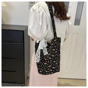 Macro shot of floral pattern fabric and white lace bow detail on a black tote bag