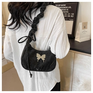 Detail of black pleated crescent bag with silver butterfly accent and drawstring shoulder strap