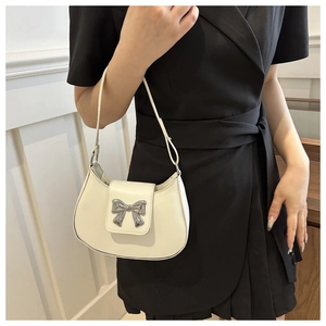 Detail of white hobo bag with silver bow buckle and fine strap on black dress