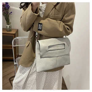 Detail of light gray crossbody bag featuring unique cutout handle and vertical stitching