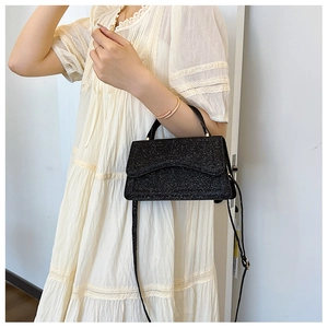Detail of black sequined crossbody bag showing glitter texture and metal magnetic clasp