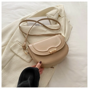 Detail of beige saddle bag with gold ring buckle on cream blazer, showing texture