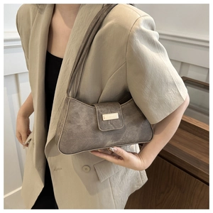 Detail of grey suede shoulder bag with gold metal buckle on a beige suit model