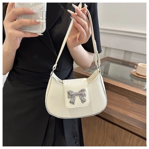 Detailed view of white hobo bag with silver metallic bow buckle and smooth faux leather finish