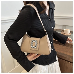 Close-up of beige leather shoulder bag with a large sparkling crystal buckle detail