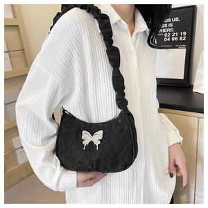 Detail of black crescent shoulder bag with pleated strap and white butterfly buckle