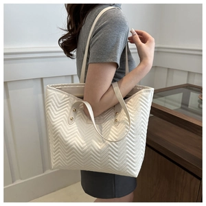 Dettaglio della borsa tote color crema con trapuntatura a onde e finitura in ecopelle PU