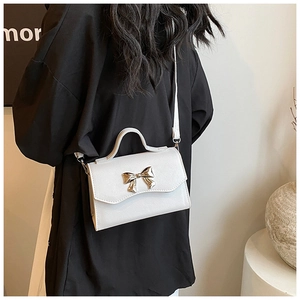 Detail of white cross-grain leather crossbody bag with a golden bow-shaped metal buckle