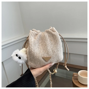 Detail of light beige woven bucket bag with drawstring closure and chain strap