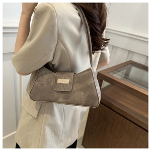 Detail shot of vintage brown underarm bag with a gold buckle and textured leather finish
