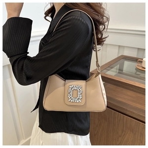 Detail of a chic beige underarm bag featuring a signature sparkling square crystal buckle