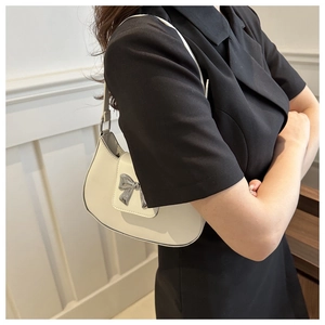 Detailed view of white leather underarm bag with a silver metallic bow decoration