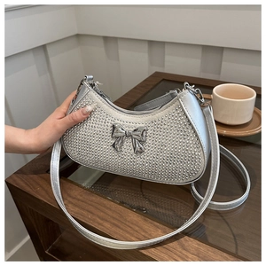 Close-up of sparkling silver rhinestone handbag with a metal bow detail and slim strap