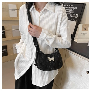 Detail of black velvet crescent bag with silver butterfly and pleated wide shoulder strap