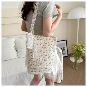Detail of floral tote bag with lace trim shoulder strap and delicate bow decoration
