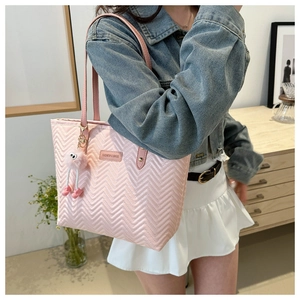 Borsa tote trapuntata rosa con ciondolo, indossata a spalla da una modella elegante