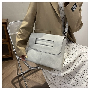 Détail du sac enveloppe bleu clair avec poignée et bandoulière réglable en similicuir