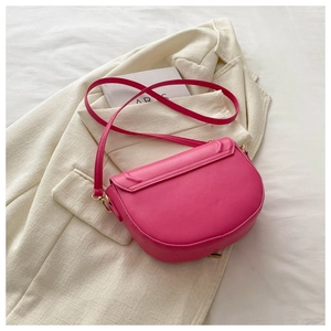 Detailed back view of a bright pink saddle bag with smooth texture and gold metal hardware