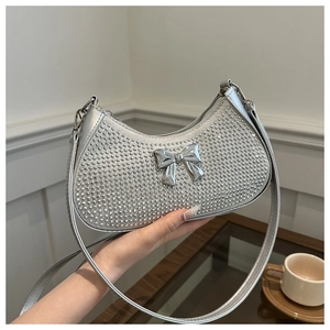 Close-up of silver rhinestone underarm bag with decorative metal bow and slim shoulder strap