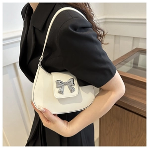 Detail of white leather shoulder bag with silver bow ornament and slim strap