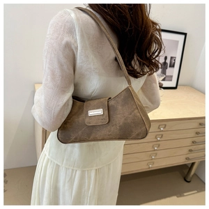 Minimalist brown retro baguette bag with metallic buckle worn over the shoulder