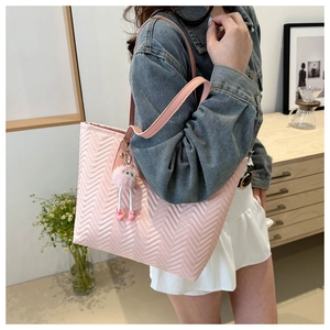 Borsa tote rosa con cuciture ondulate e un ciondolo decorativo a forma di palla di pelo