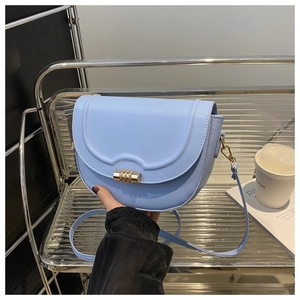 Close-up of light blue saddle bag with golden metallic clasp and smooth leather texture