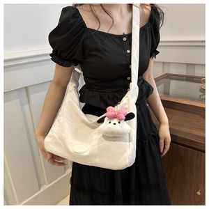Détail du sac cabas blanc avec texture froncée, sangle réglable et petit pendentif peluche