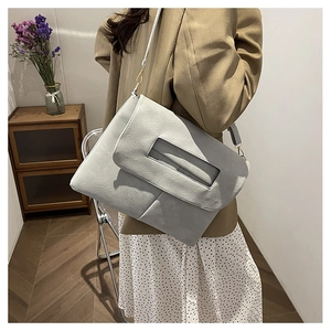 Détail du sac à bandoulière gris clair en cuir plissé porté avec un blazer brun et une jupe
