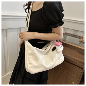 Détail du cabas minimaliste crème à texture souple et breloque en peluche mignonne