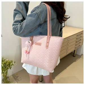 Detail of pink quilted tote bag with V-shaped stitching and fashion brand leather tag