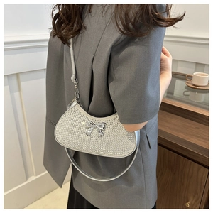 Detail of silver rhinestone crescent bag with metallic bow and slim leather strap