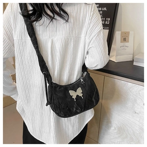 Detailed view of black ruched shoulder bag featuring a silver butterfly metallic ornament