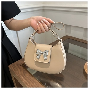 Detail of hobo bag with silver bow ornament and smooth beige synthetic leather texture