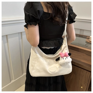 Détail du sac cabas blanc texturé avec un joli pendentif chiot en peluche doux