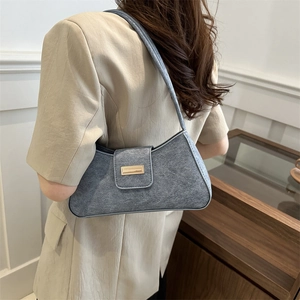 Minimalist grey suede shoulder bag with gold buckle accessory on a fashion model