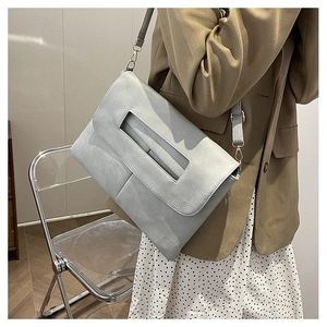 Détail du sac enveloppe gris montrant la poignée métallique et la sangle réglable en PU