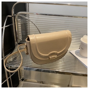 Detail view of beige saddle bag with metallic turn-lock and smooth matte leather finish
