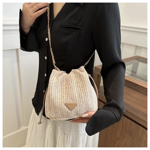 Close-up of woven straw bucket bag showing fine texture and golden chain strap