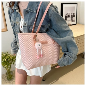 Detail view of pink quilted tote bag with cute monster charm and leather brand tag