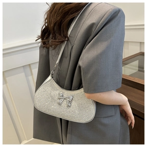 Detail of silver rhinestone shoulder bag featuring a metallic bow and crescent design