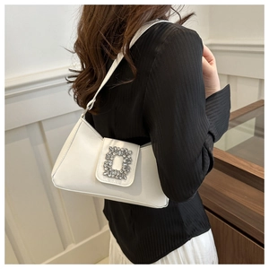 Detail of white leather shoulder bag featuring a luxury crystal-encrusted square buckle
